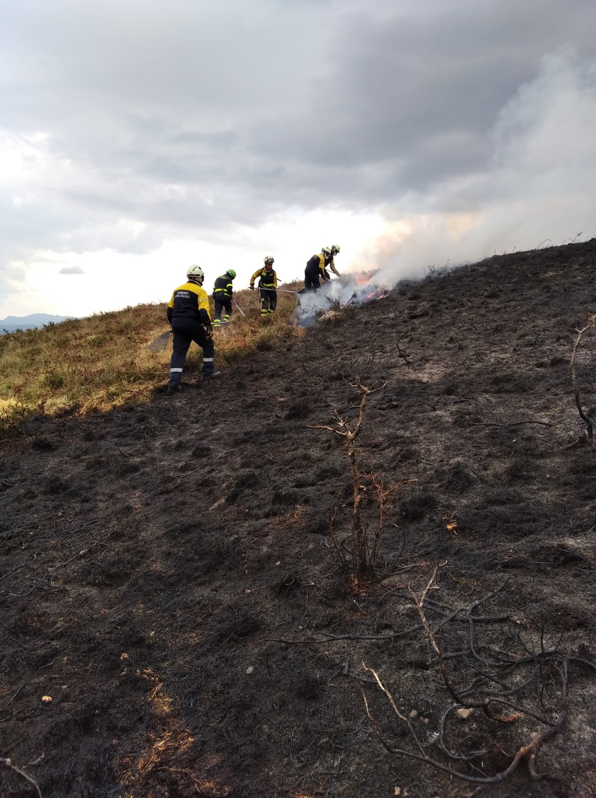Bomberos trabajan en una quema de pastos de montaña.