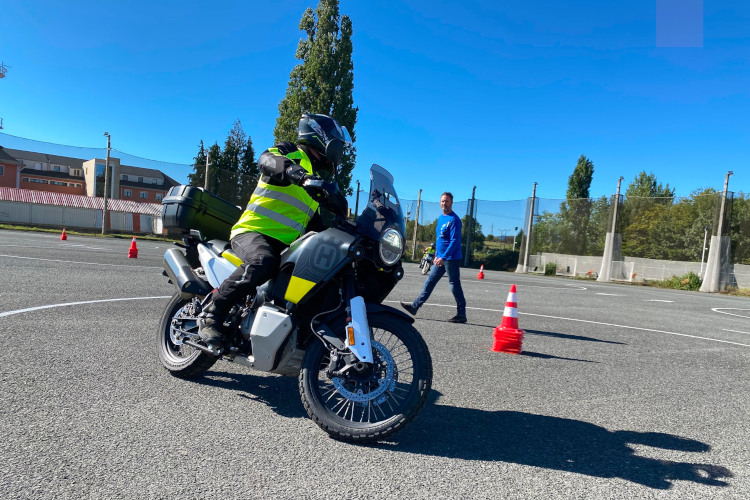 Una persona conduce una moto y recibe instrucciones durante un curso.
