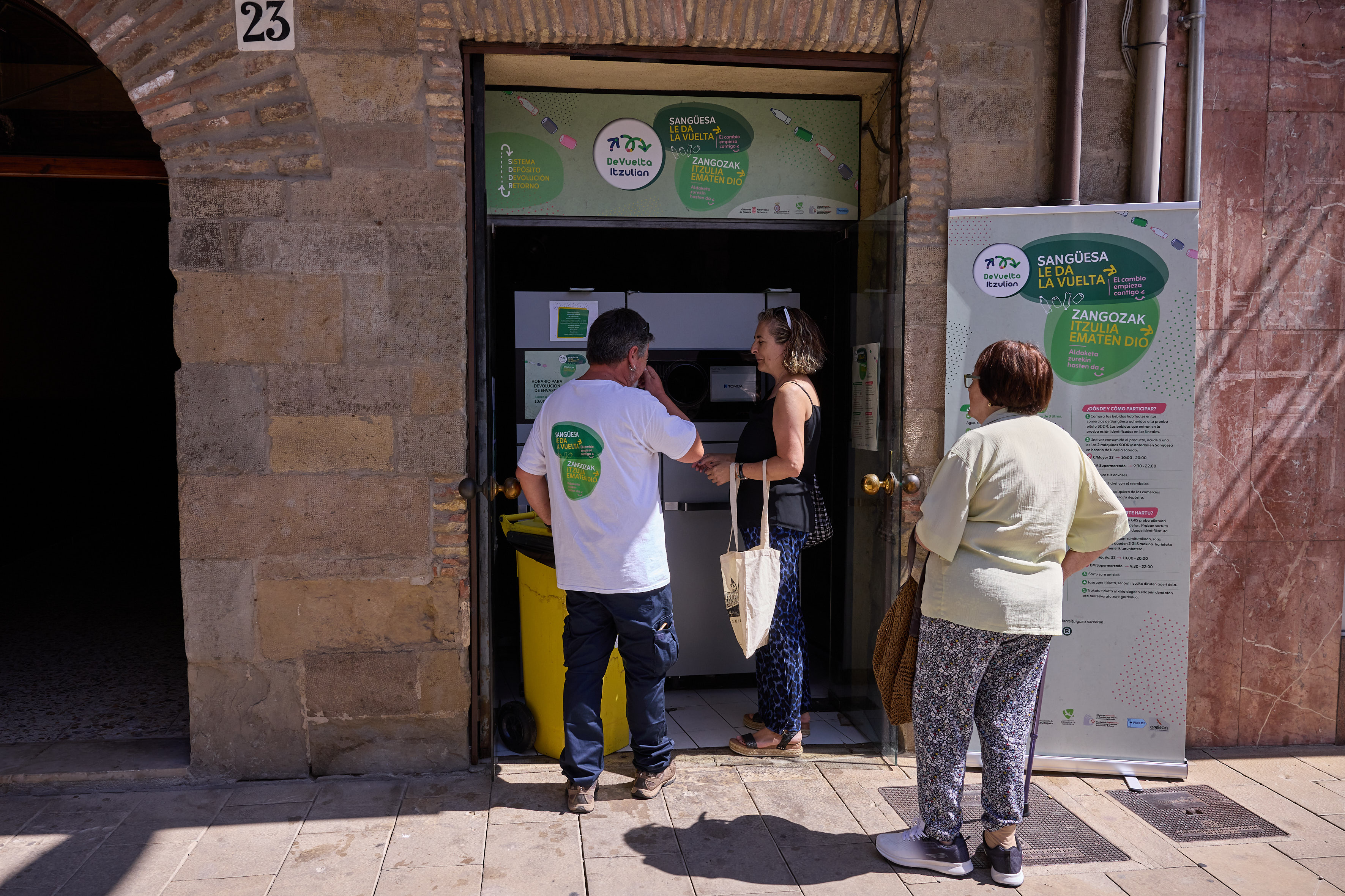 Vecinos de Sangüesa utilizando la maquina inversa de depósito de botellas y latas